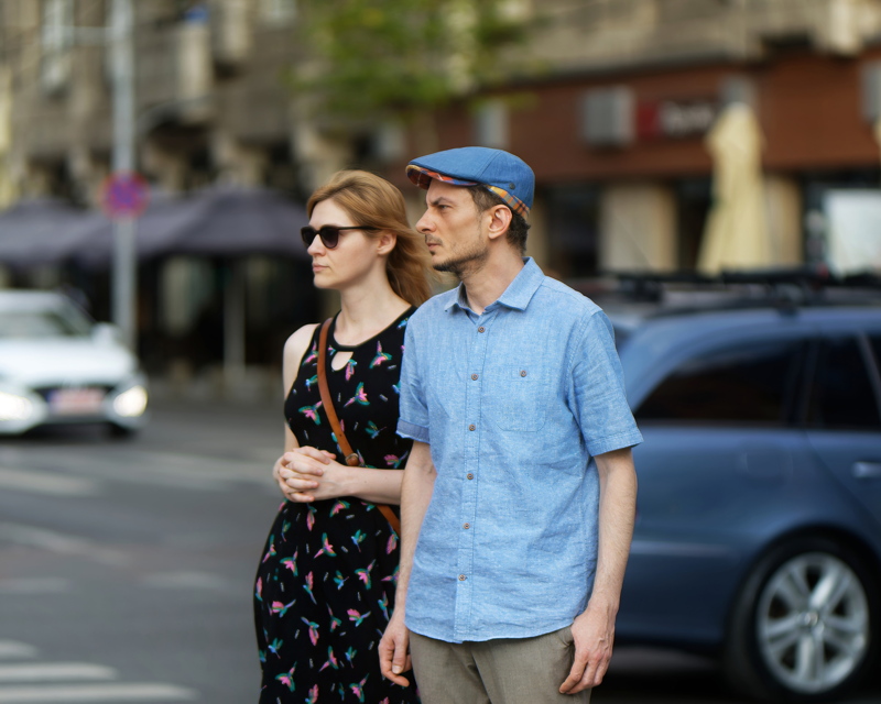 25 - A couple standing outdoors on a city street with a blurred urban background